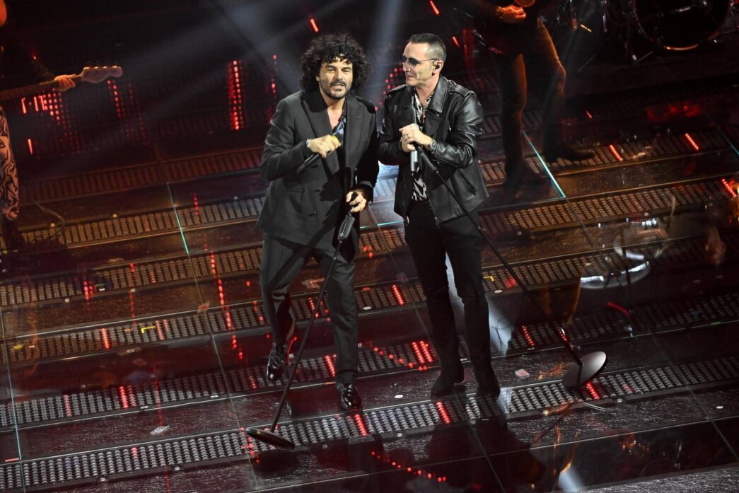 ALT: "Kekko e Renga si scambiano un bacio emozionante dopo la loro esibizione al Festival di Sanremo 2025, sorprendendo il pubblico."
